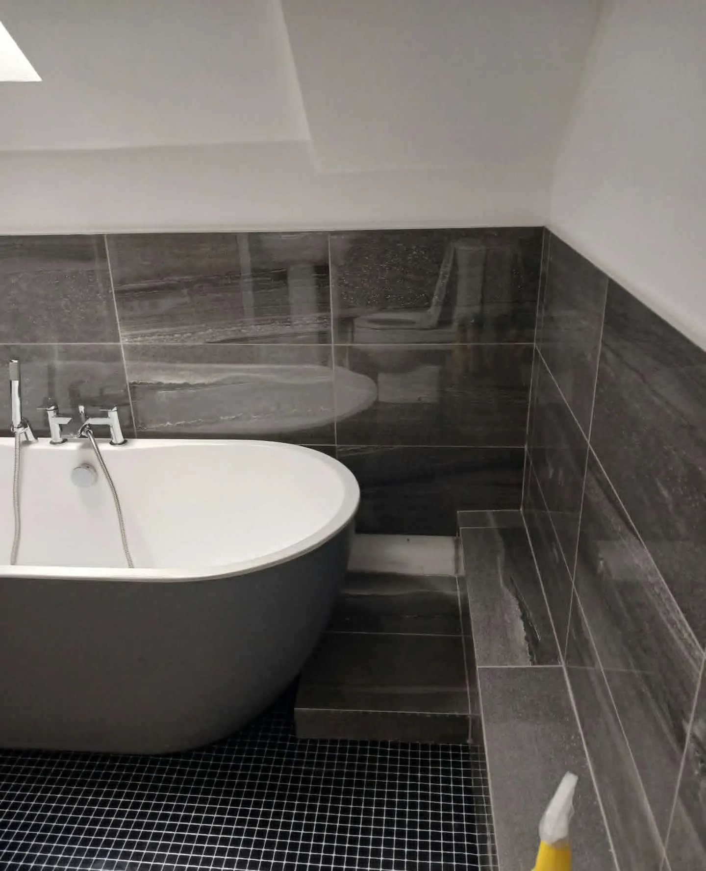 Grey tiled bathroom with freestanding bath