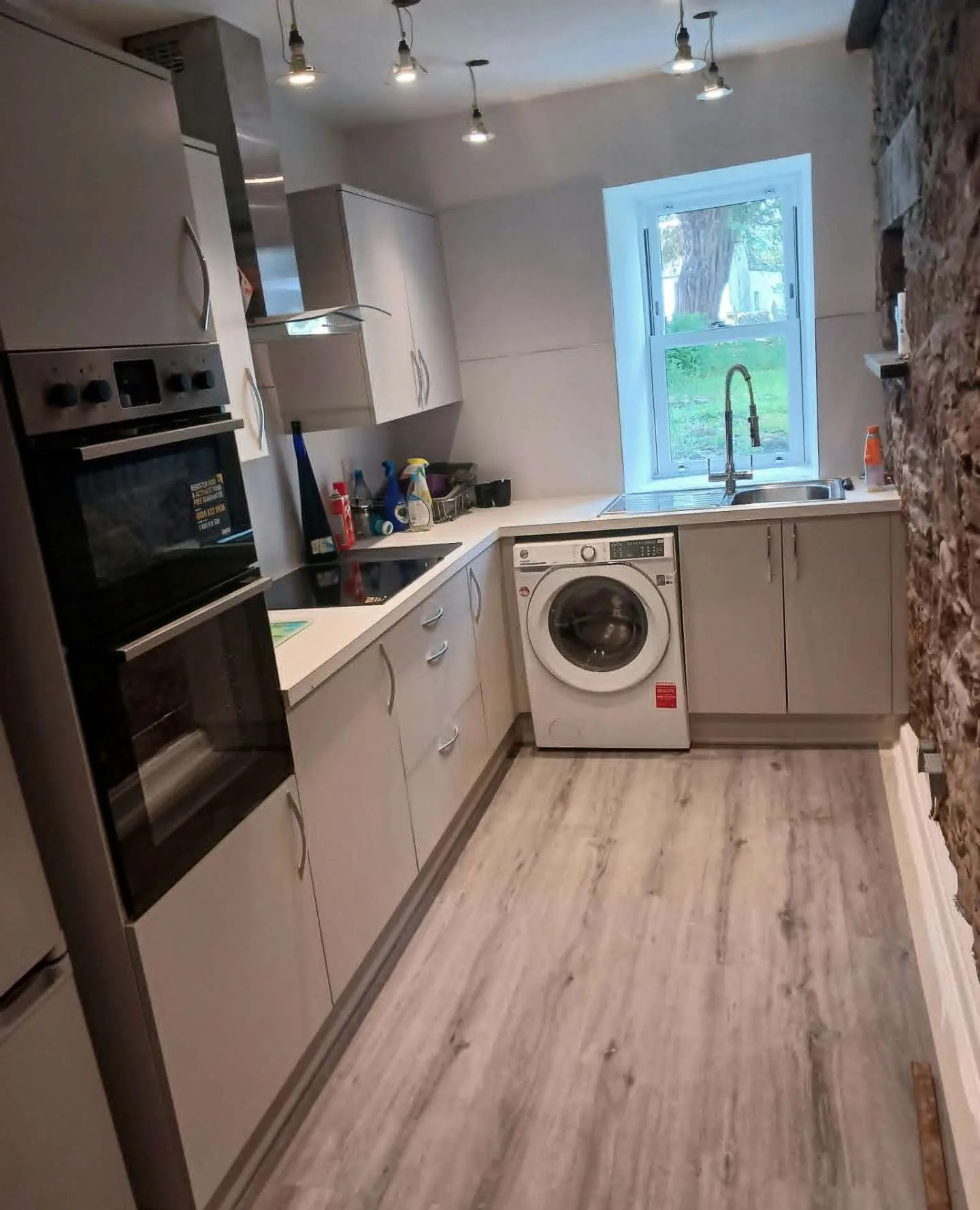 Grey kitchen with stone wall by Siga Building Services Joinery